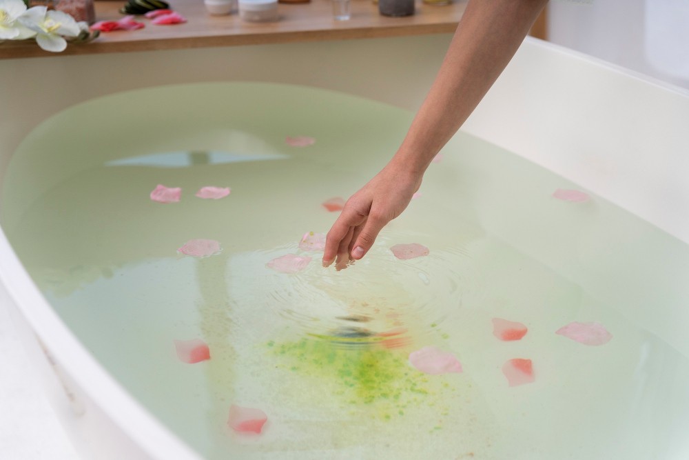 young-woman-putting-rose-petals-water-before-taking-bath