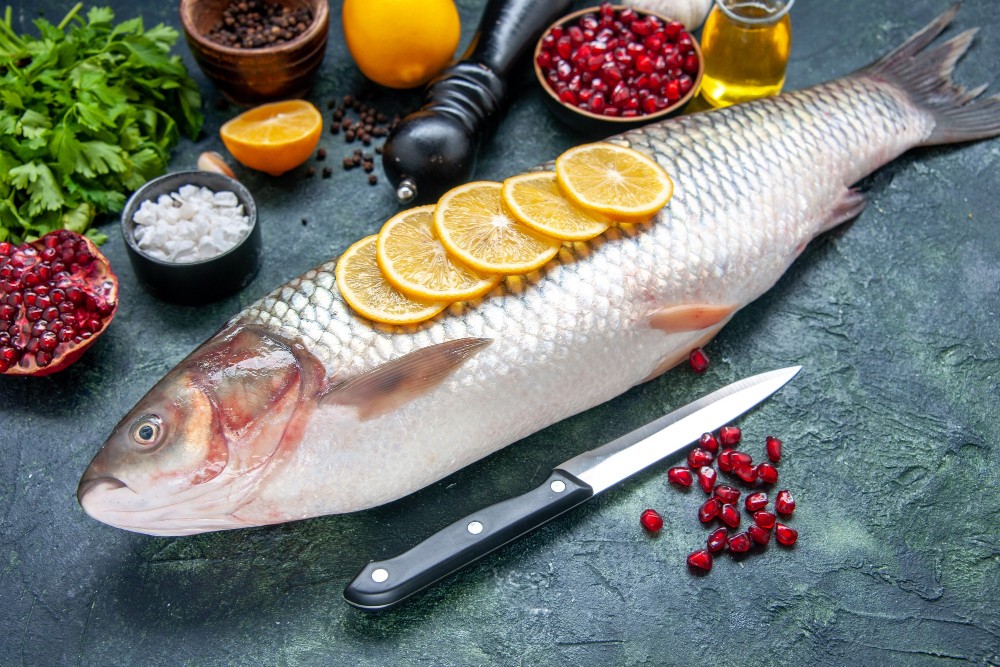 bottom-view-fresh-fish-with-lemon-slices-knife-kitchen-table