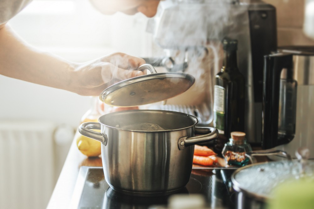 young-man-cooking-fresh-food-home-opening-lid-steaming-pot